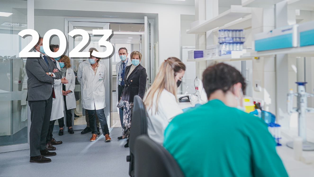 interior sala laboratorio con dos investigadores sentados a la derecha y otras personas de pie a  la izquierda