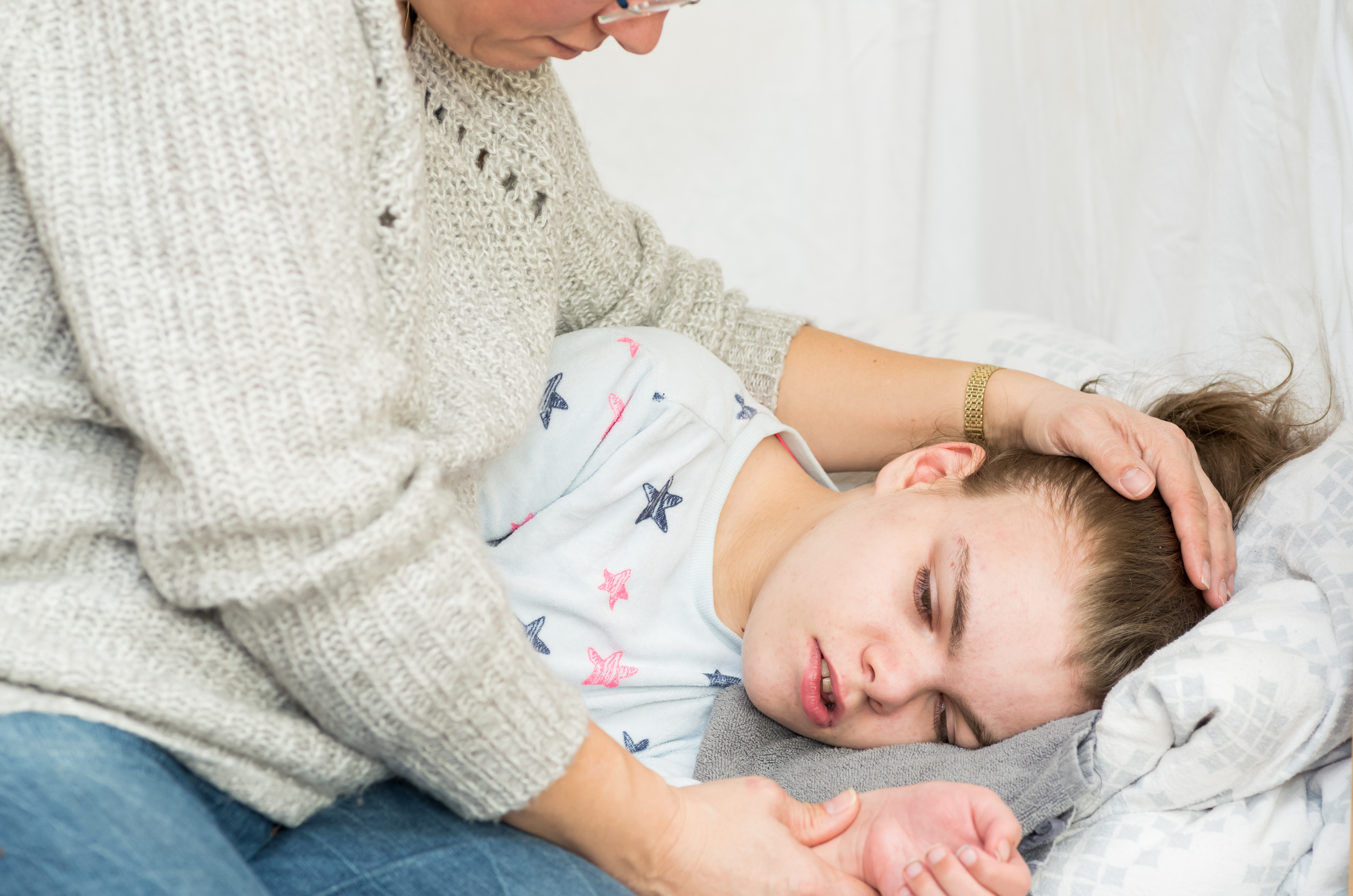 cara de una niña sobre la almohada sostenida por las manos de una mujer