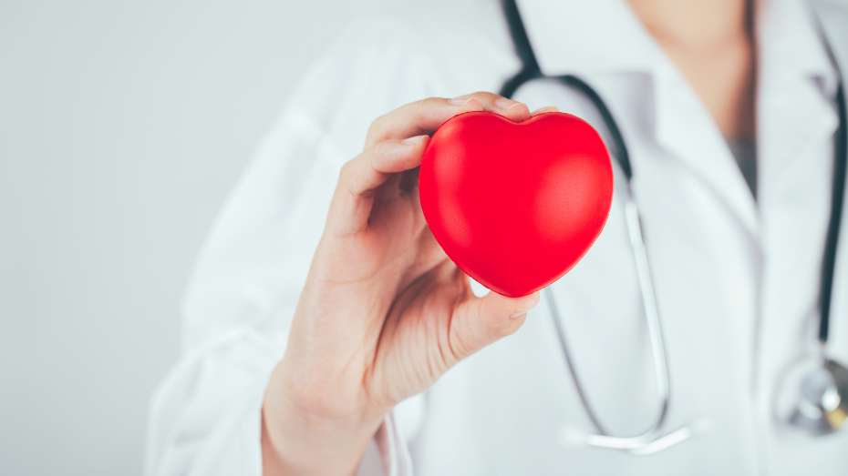 médica que sostiene un corazón de goma en la mano