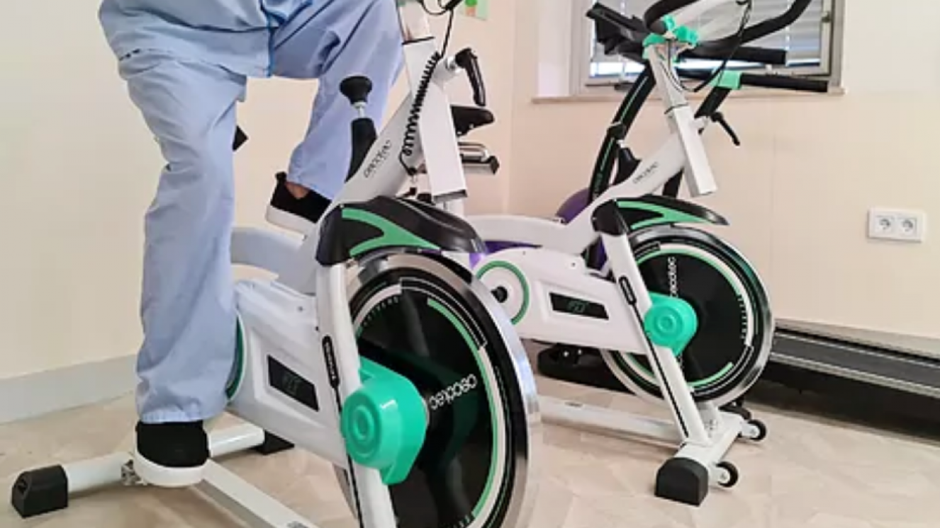 Parte inferior de dos bicicletas estáticas una de ellas con una persona con pijama azul