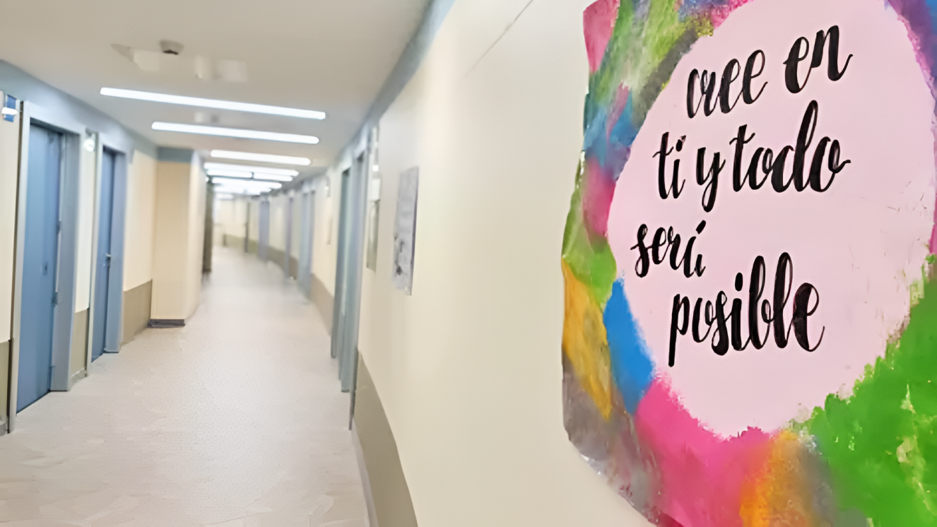 Imagen de pasillo en amarillo claro con una pintura de colores en la pared derecha con un texto Cree en ti y todo será posible