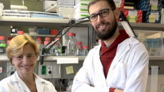dos investigadores, mujer a la izquierda y hombre a la derecha delante de laboratorios