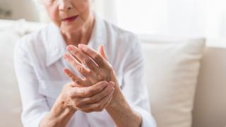 mujer anciana se coge una mano con la otra como si le doliera