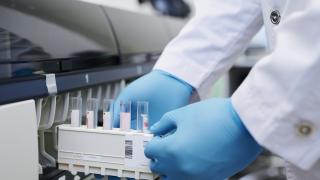 Manos con guantes azules que introducen dispositivo con tubos en una máquina