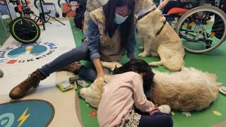 Terapia con perros niña echada en el suelo con un perro y al lado su madre