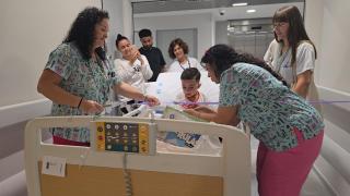 Traslado pediatría un niño en una cama  con profesionales alrededor por un pasillo