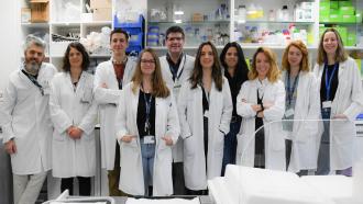 Grupo de médicos posando de frente con laboratoio detrás