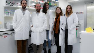 Grupo de médicos posando de frente con laboratoio detrás