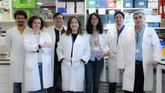 Grupo de médicos posando de frente con laboratoio detrás