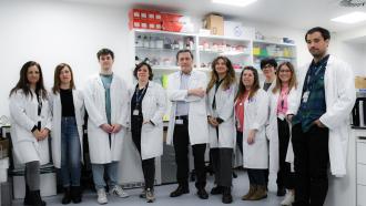Grupo de médicos posando de frente con laboratoio detrás