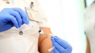 Mano de sanitaria que extrae medicamento de un frasco con una jeringa