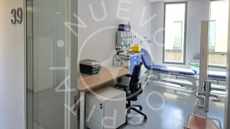 Consulta de Pediatría con silla y mesa en primer término y al fondo camilla