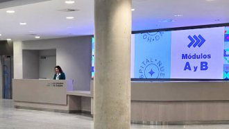 Unidad de información al fondo con profesional detrás de mesa y detrás pantalla