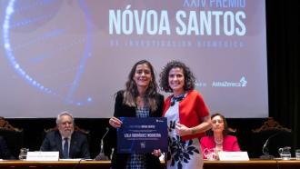 Dos mujeres en un escenario la  izquierda sostiene un diploma