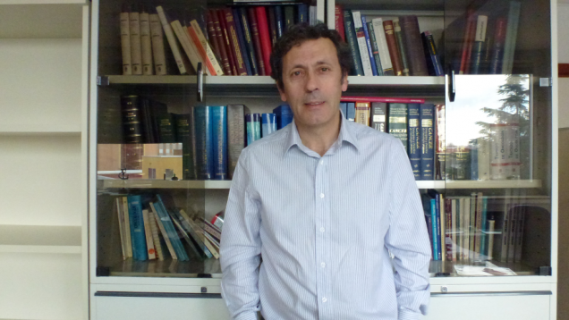 hombre con camisa a rayas, moreno, mediana edad con fondo de librería