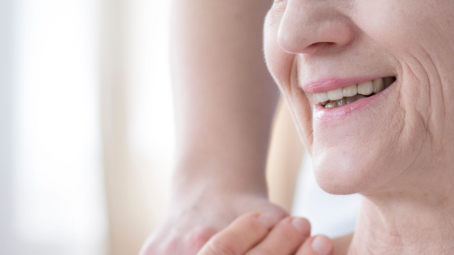 sonrisa de mujer mayor de lado y mano que se posa en su hombro