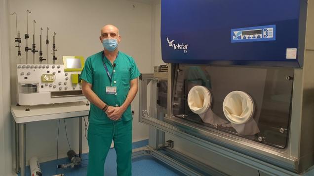 Un profesional sanitario con pijama verde al lado dedos máquinas en una sala blanca sanitaria