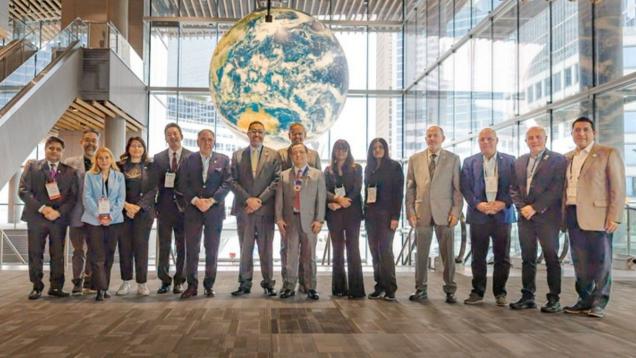 Grupo de personas posando de frente en línea y debajo de una especie de bola del mundo